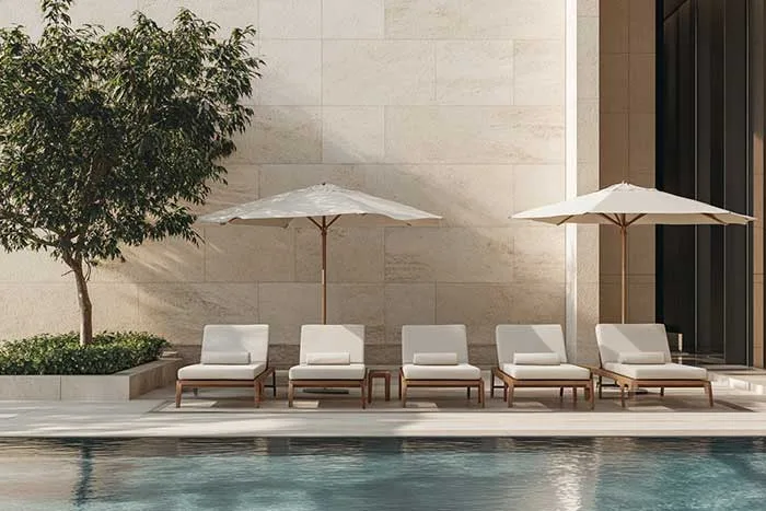 Five cushioned loungers and two umbrellas arranged beside a swimming pool