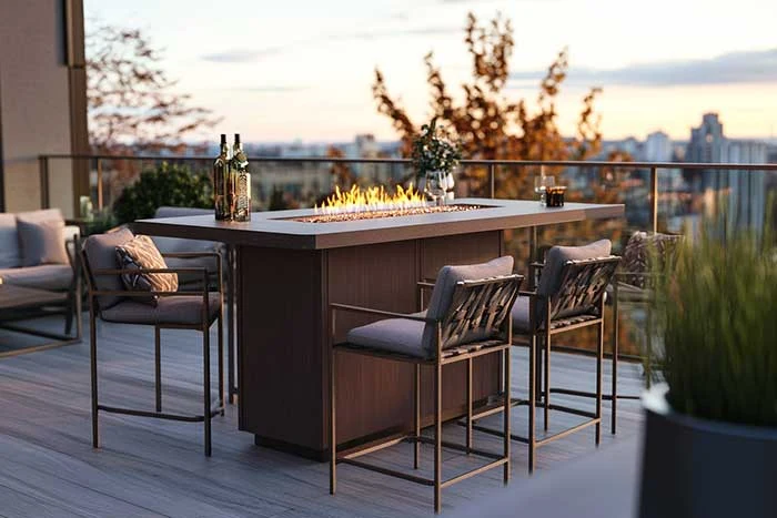Rooftop high table with four stools and a central fire feature on a planted terrace