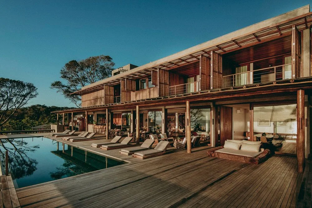 Coastal resort building beside a pool deck with loungers and covered seating